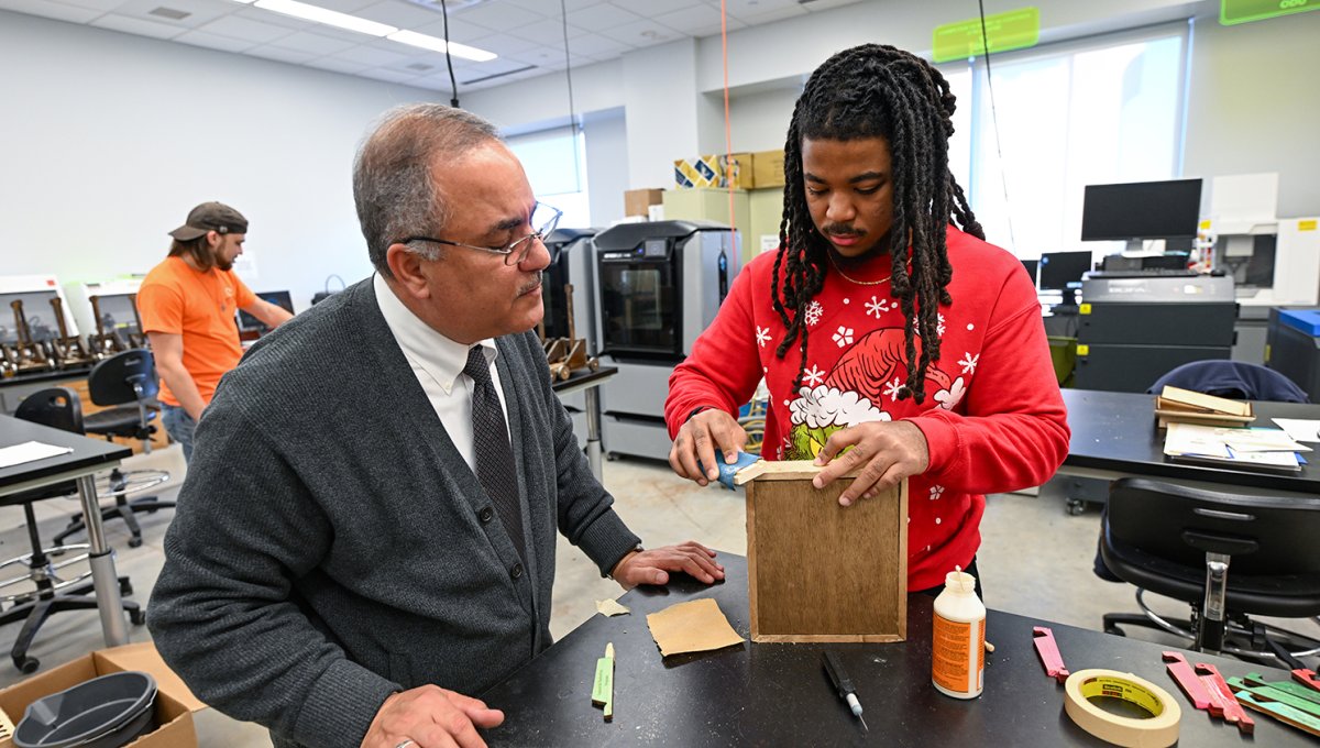 Student Isaiah Washington shows Dr. Matrood how he is sanding the toy he has created.