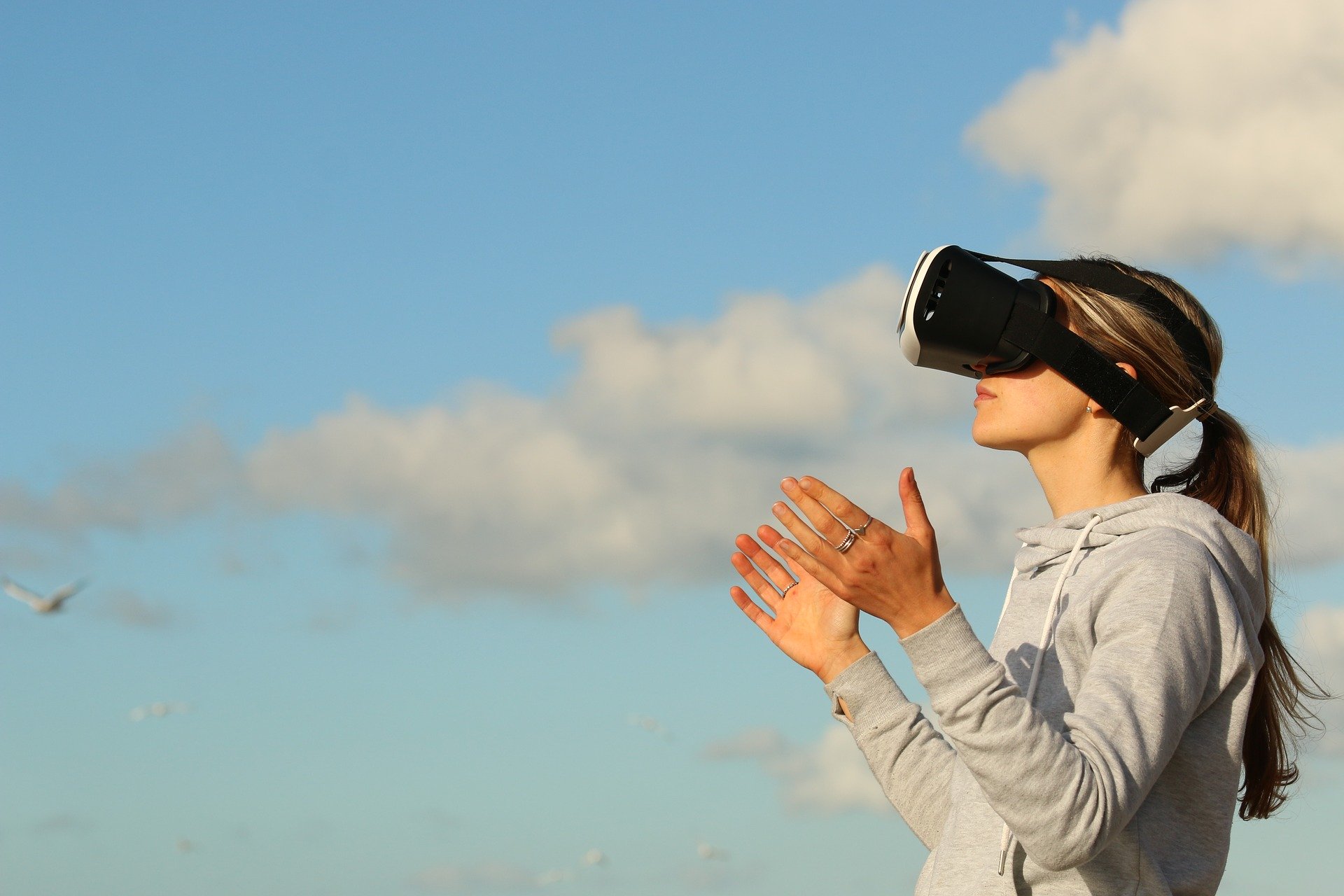 Woman with virtual reality headset, clouds in background