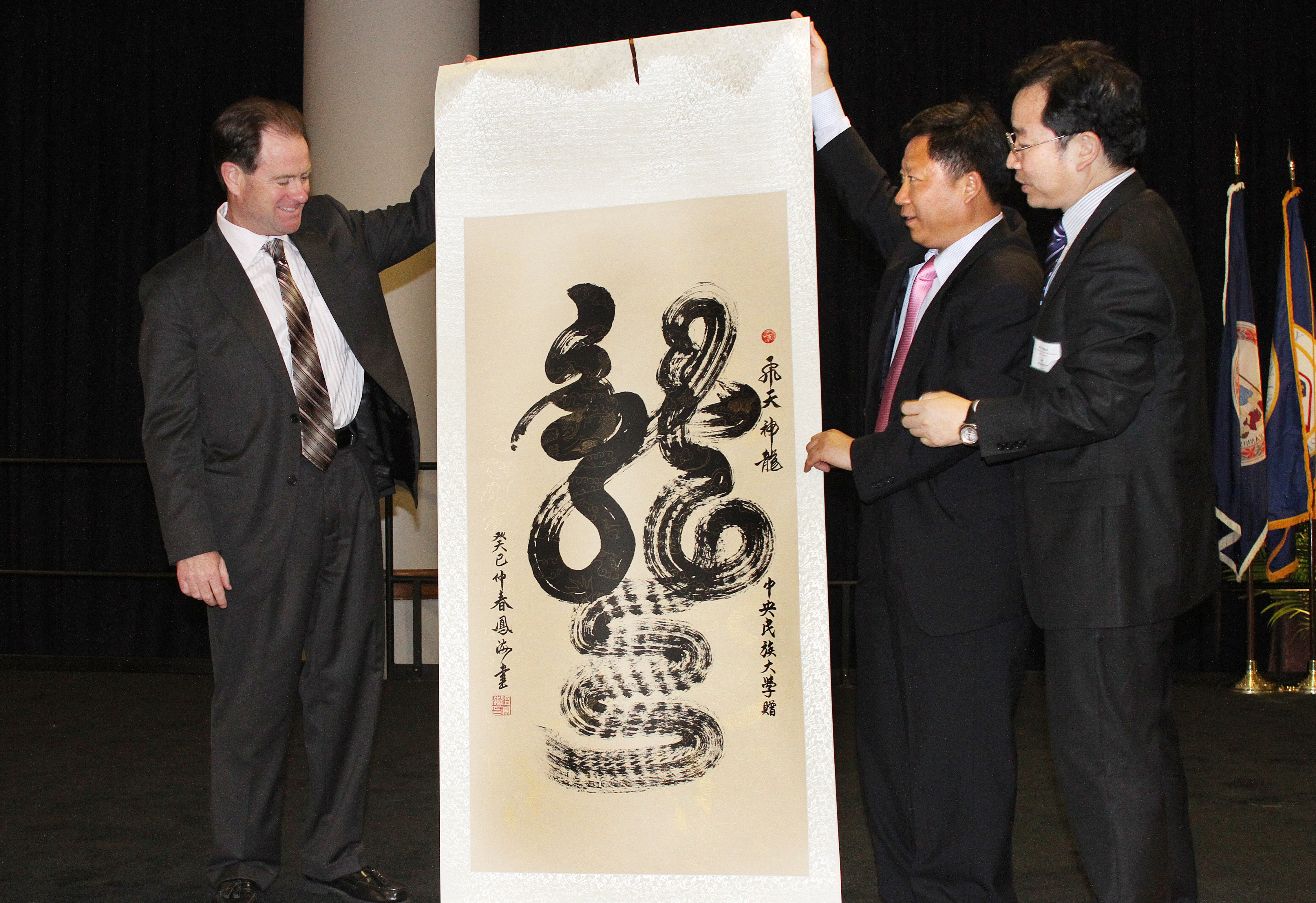 Photo of ODU President John R. Broderick accepting a decorative scroll from representatives of Minzu University, of China.