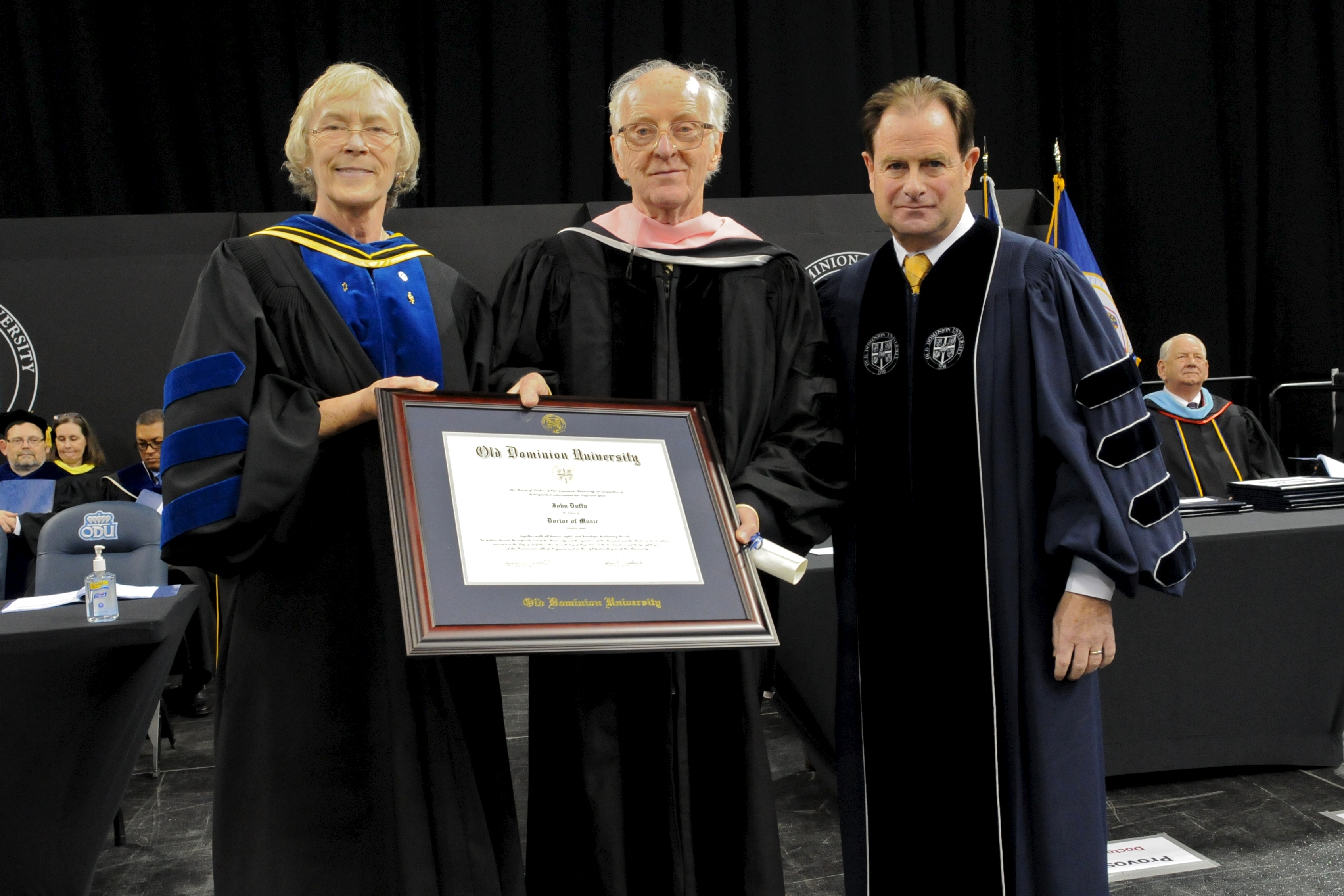 Provost Carol Simpson and President John Broderick present an honorary doctorate to composer John Duffy.