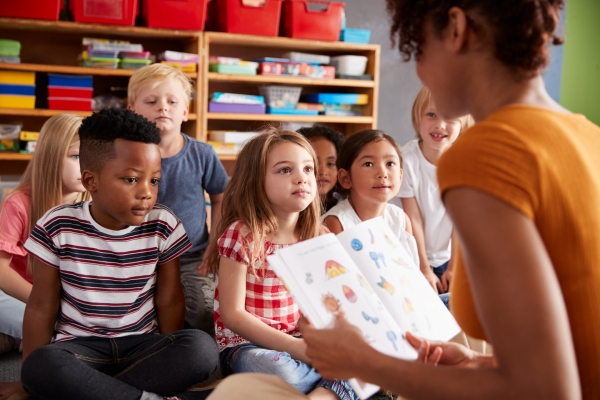 Group Of Elementary School Pupils Sitting On Floor Listening