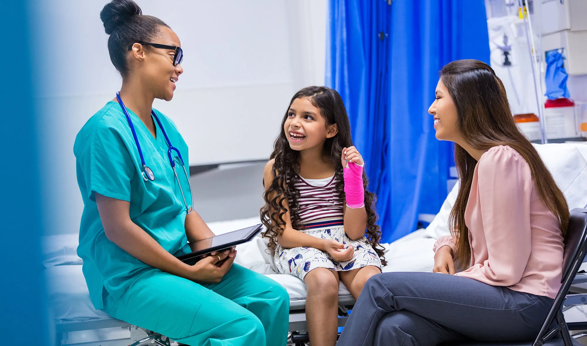 A fellow talks with a patient with a broken wrist and her mo
