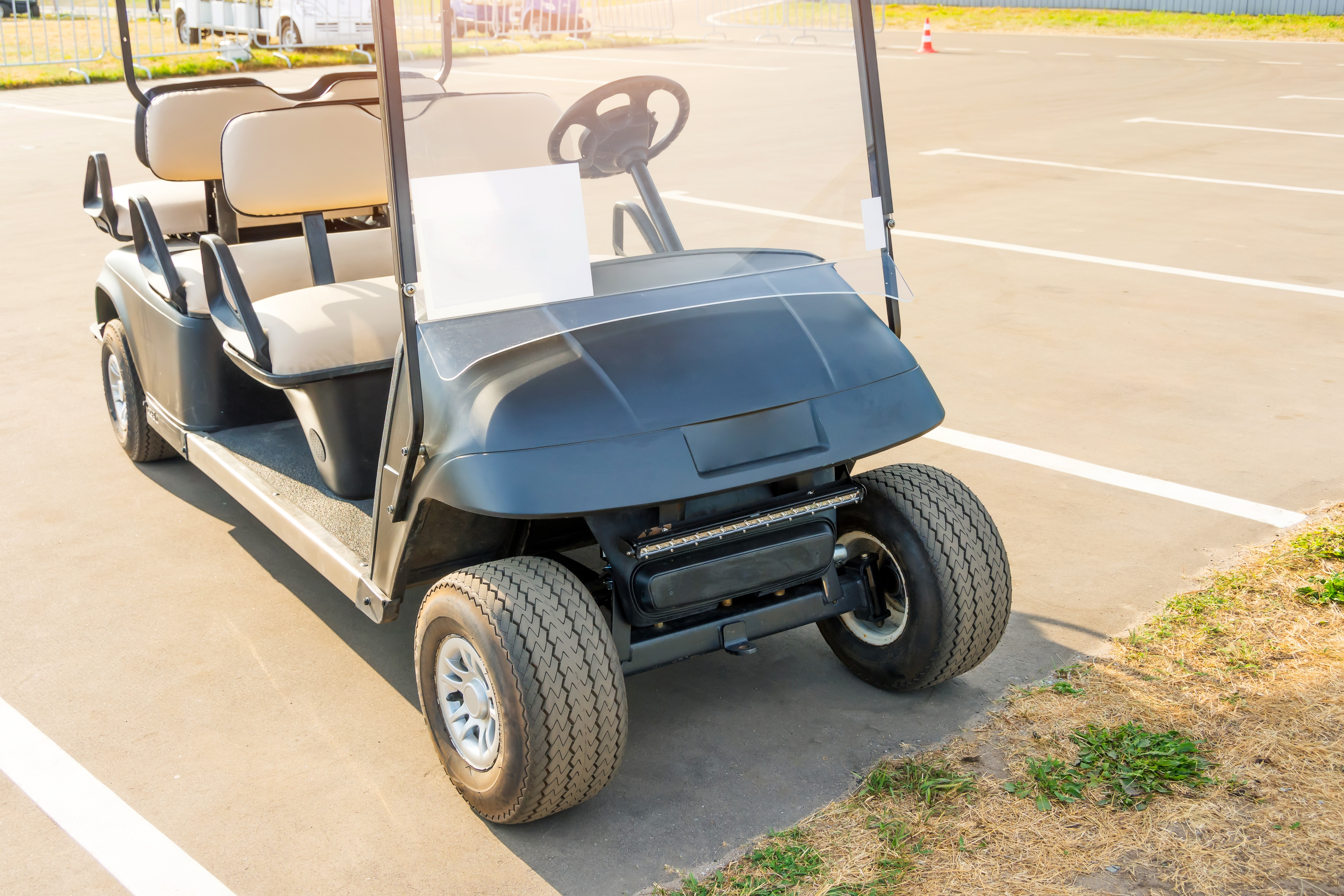 Golf cart parked in parking lot on sunny day.
