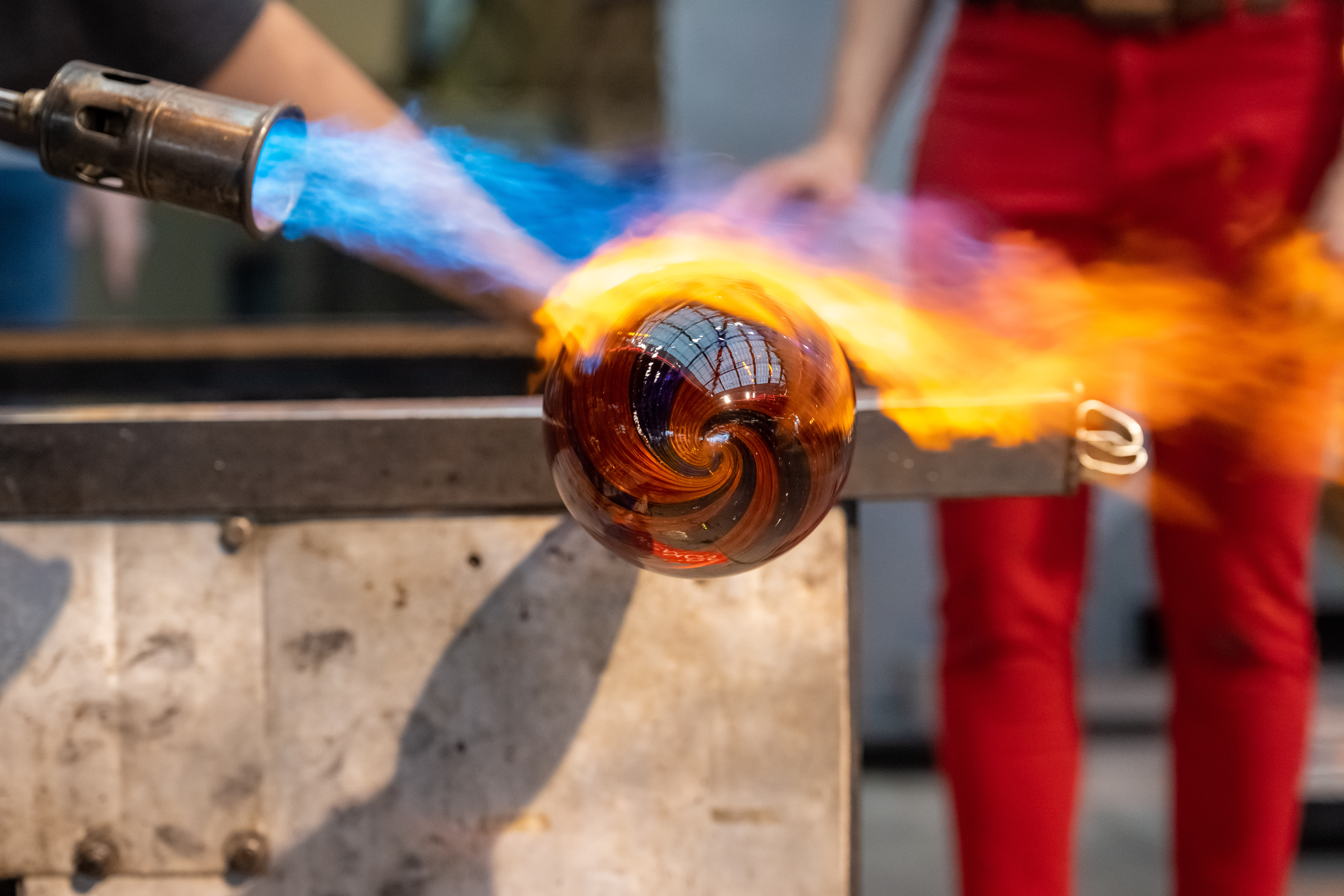 Man heats up glass with blow torch.