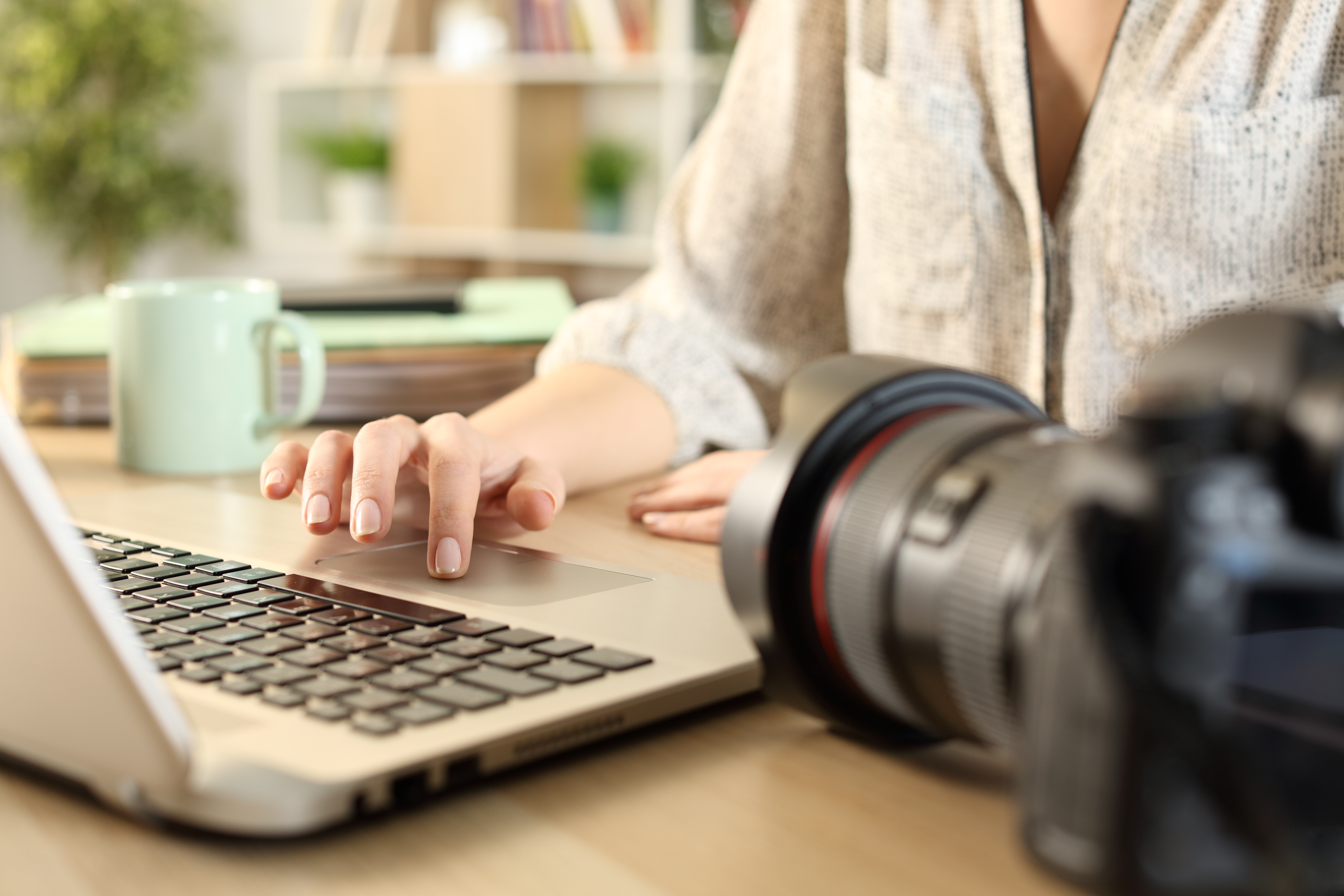 Woman types on laptop beside camera
