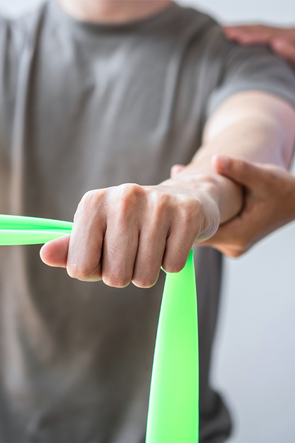 Physical Therapist helps male patient use resistance band