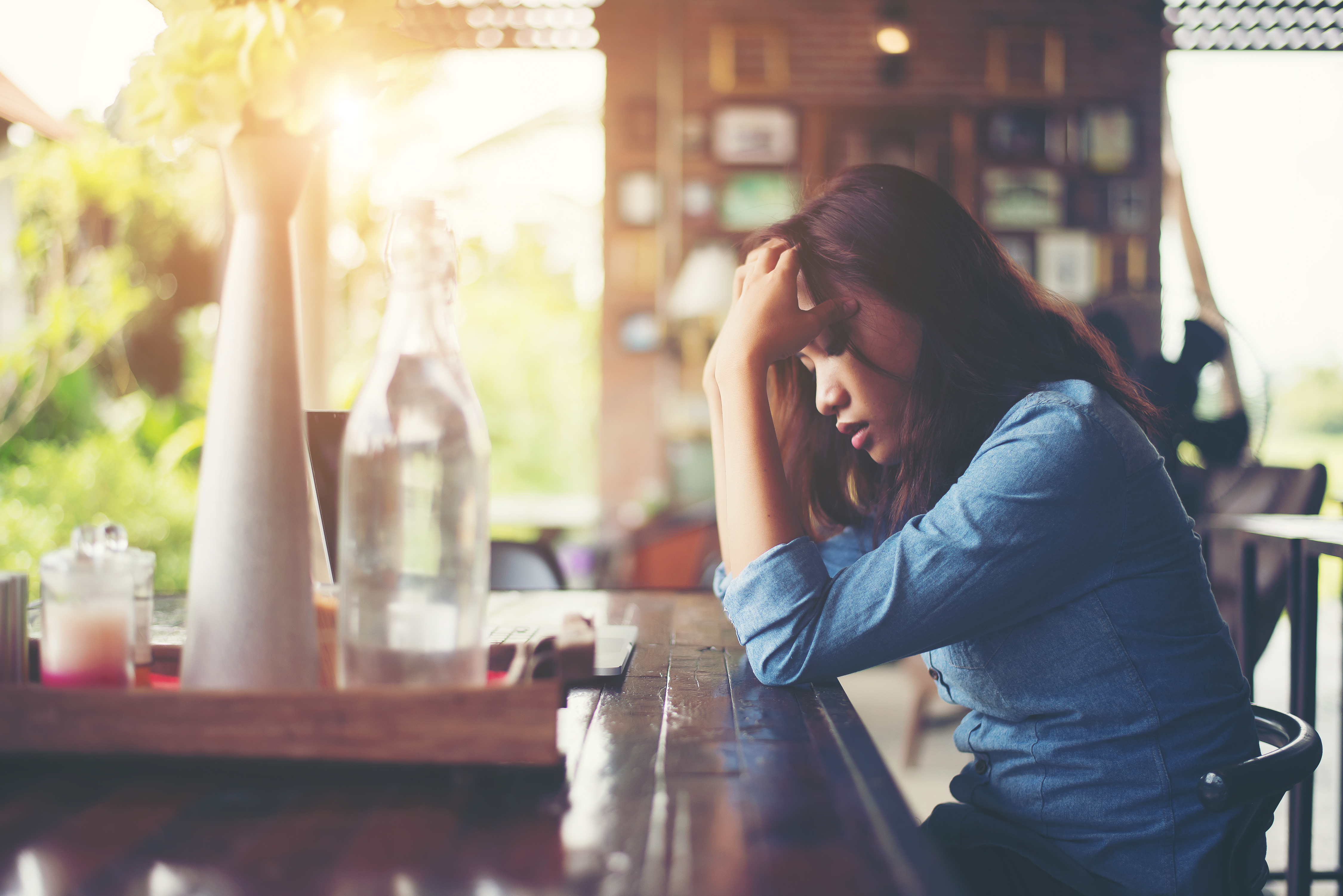 Young woman sitting in a cafe with her laptop, Stressful for work.