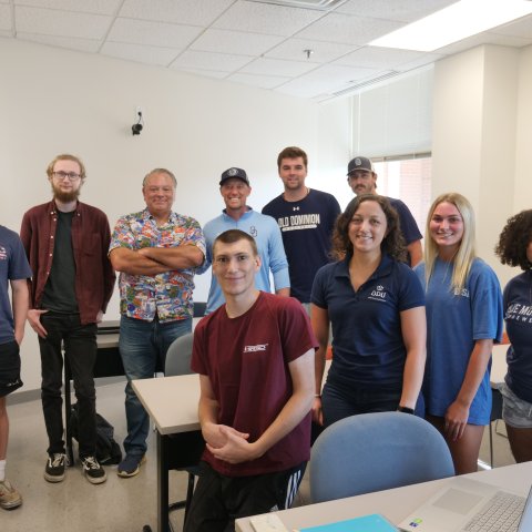 A group of students stand in a classroom.