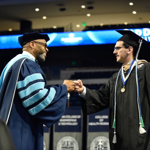 ODU President Brian Hemphill congratulates a Strome business graduate during commencement cermony