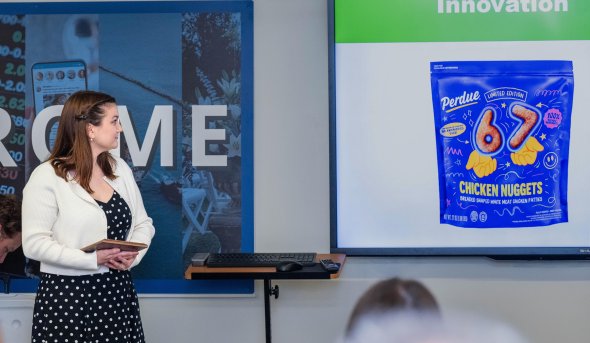 Student stands in front of class looking at Perdue produce