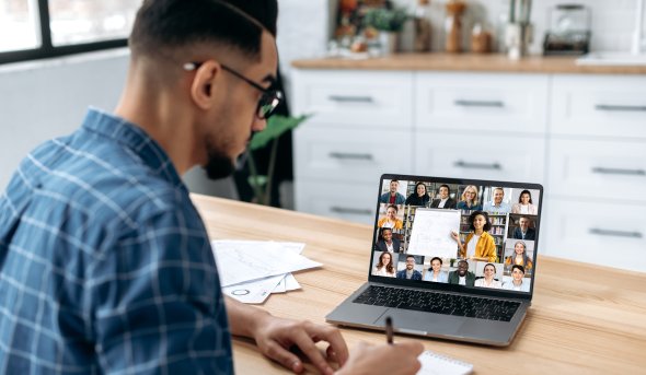 A person in front of a laptop engaging with a group of people online