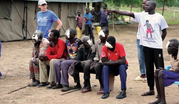 woman stands next to people sitting and one person pointing 