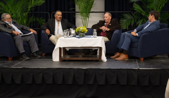 Four men sitting together on stage