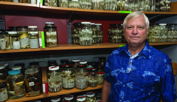 a man stands in front of specimen jars 