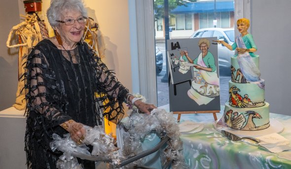 A woman poses next to a piece of artwork.