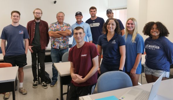 A group of students stand in a classroom.