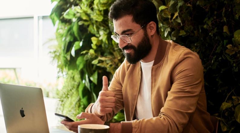 Man working on laptop giving thumbs up