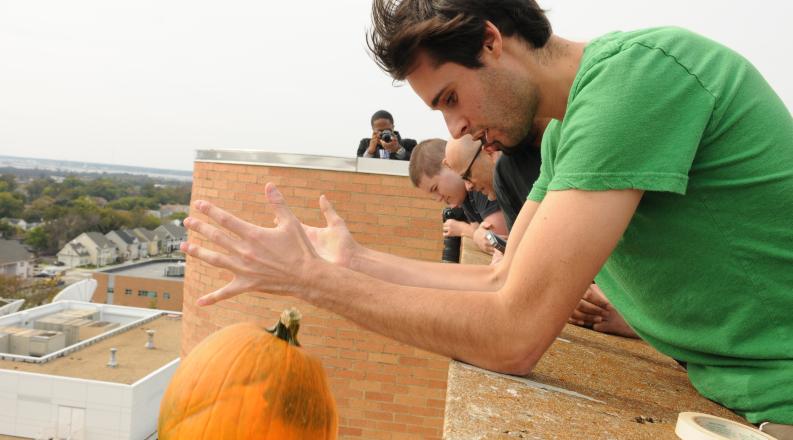 Student dropping a pumpkin off a roof