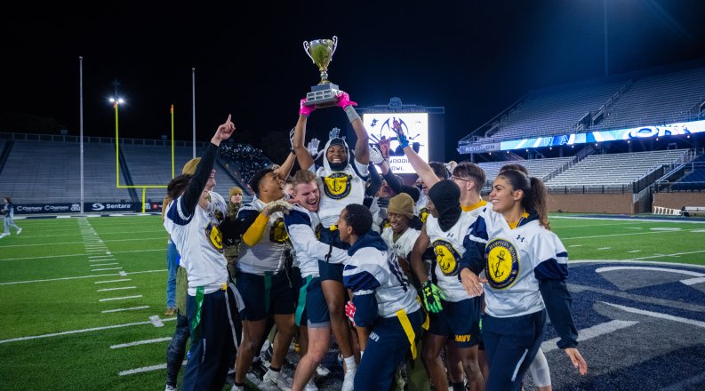 A group of people hold up a trophy.