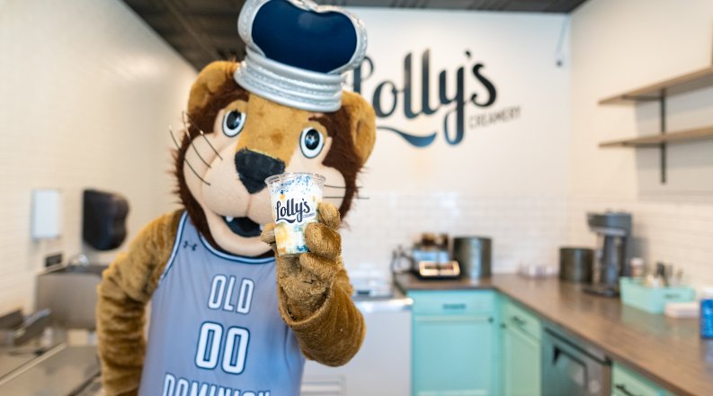 A lion mascot holds up a cup of ice cream.