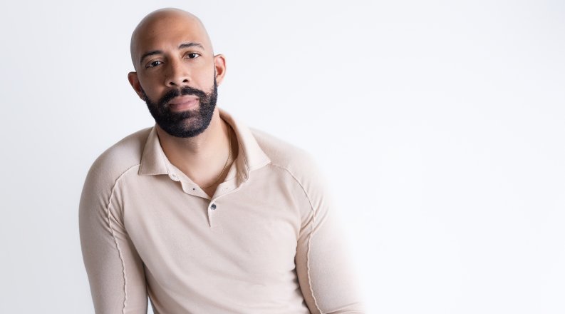ODU alumnus Damien Geter sits in front of a white backdrop. 