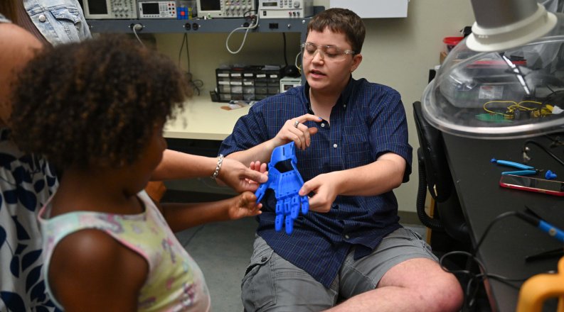 Jacob Lamkhidda shows a girl a prototype of a prosthetic hand