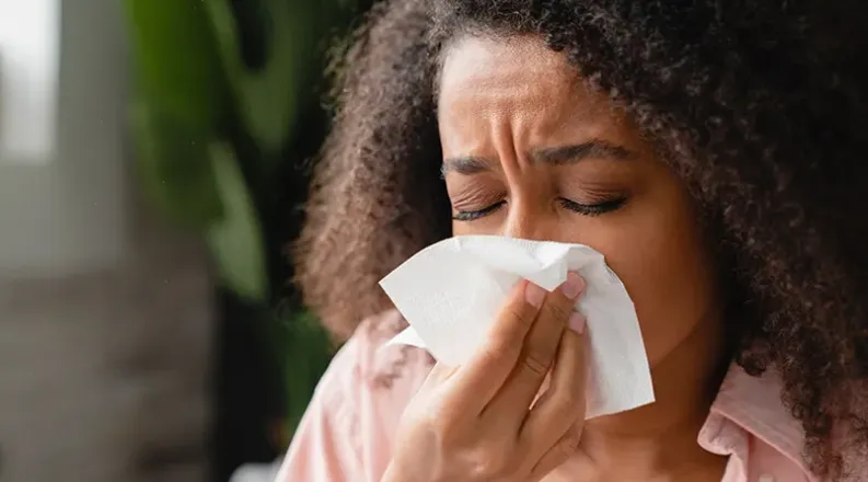 Woman sneezing into tissue