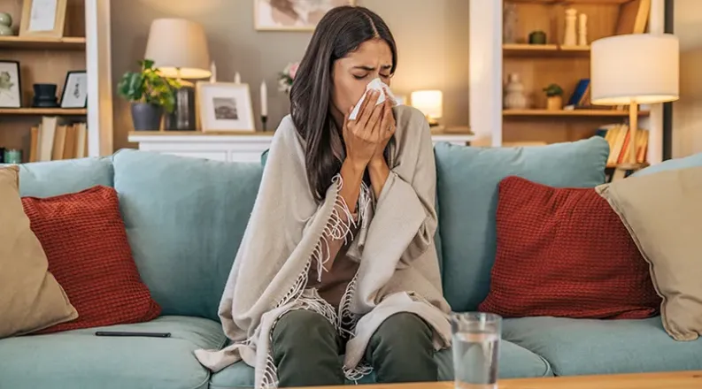 Woman sneezing on couch