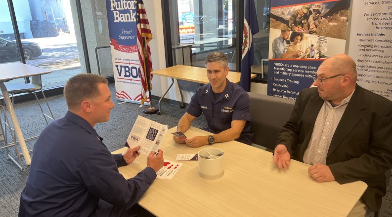 Three men review Veterans Business Outreach Centers brochures 