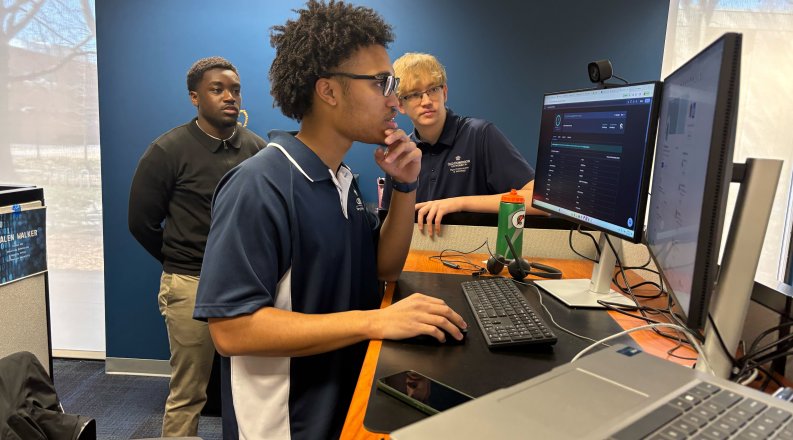 Three people at a computer