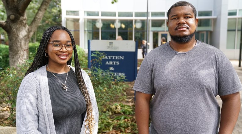 Two people stand in front of a building on ODU's campus.