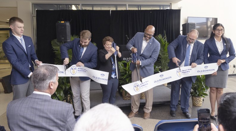 Five people at a ribbon cutting event. 