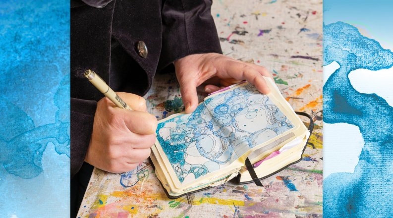 A person's hand holds a pen and draws in a small notebook 