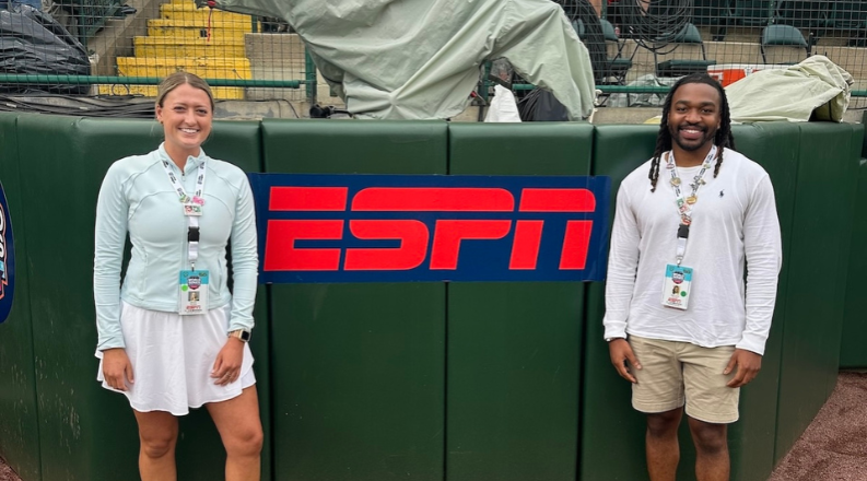 Two people stand in front of a sign that reads "ESPN."