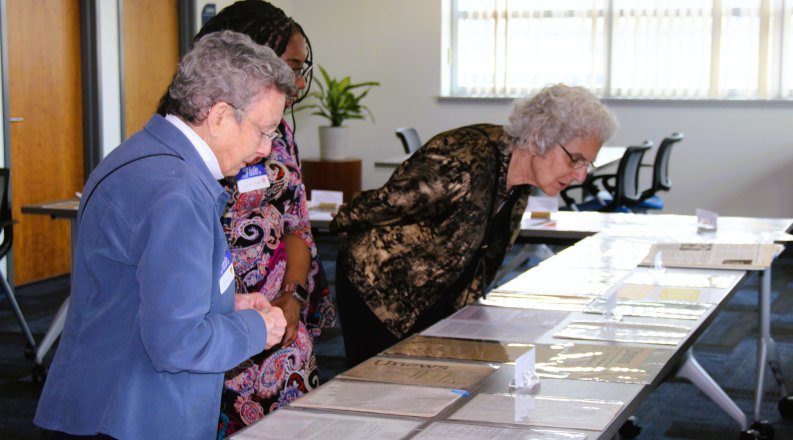 Three people look at archives of the ODU Women's Caucus.