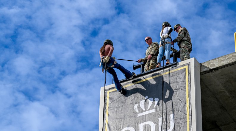 A person rappels down the side of a building.