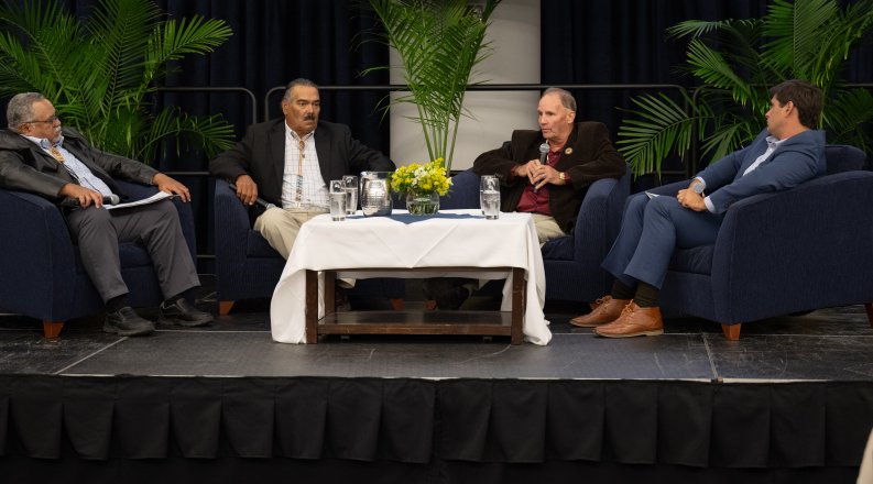 Four men sitting together on stage