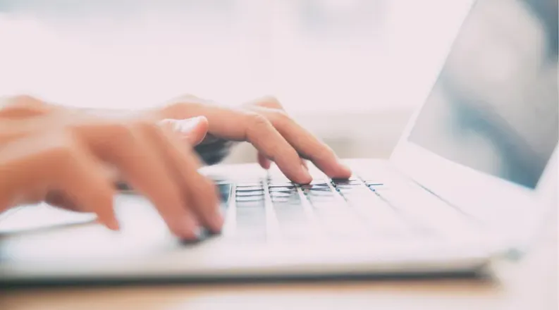 Hands typing on laptop