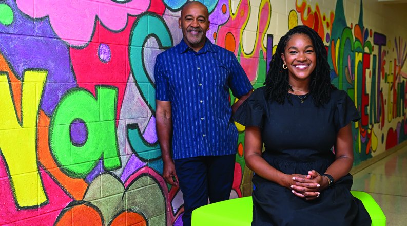 a man and woman stand in front of colorful wall 