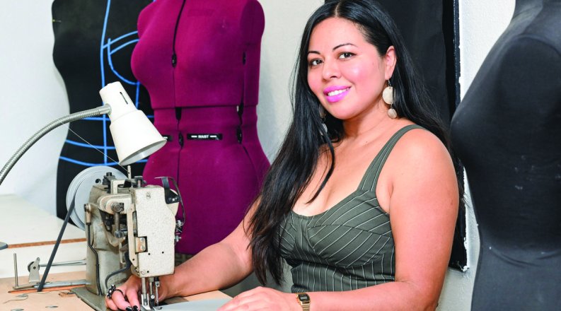 a woman sits at a sewing machine 