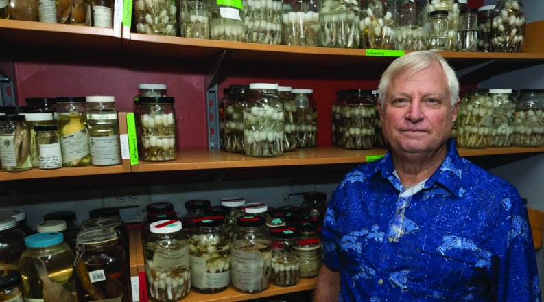 a man stands in front of specimen jars 