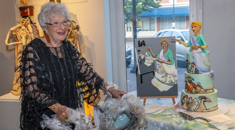 A woman poses next to a piece of artwork.