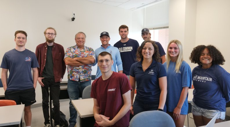 A group of students stand in a classroom.