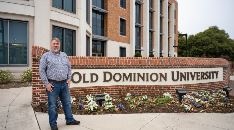 ODU alumnus Rob Wilber in front of a sign that reads Old Dominion University 