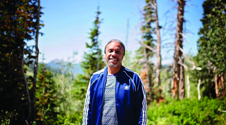 a man stands outside with trees in the background 