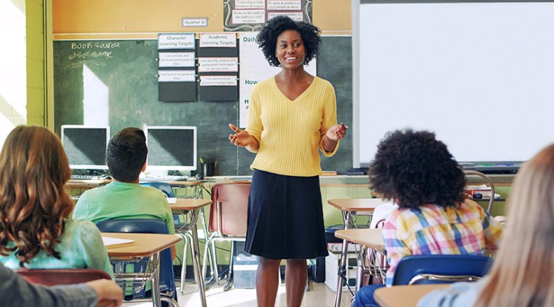 A teacher smiles while instructing a class.