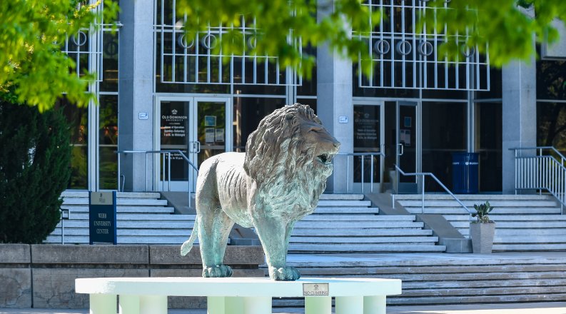 Photo of a college building with a lion statue in front