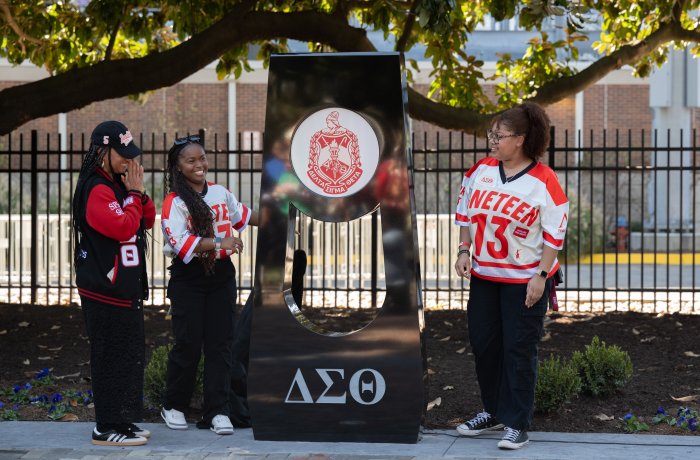 A group of people stand next to a statue.