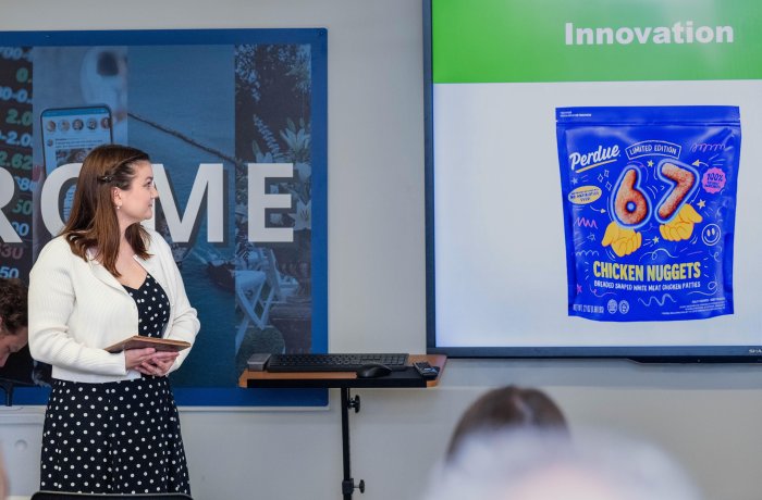 Student stands in front of class looking at Perdue produce