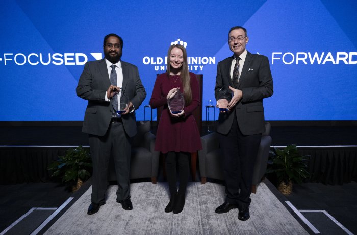 Three people holding awards in front of a screen that reads "forward-focused" 